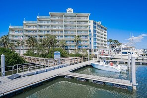 Un hotel frente al agua con varios balcones, un muelle y varias embarcaciones.