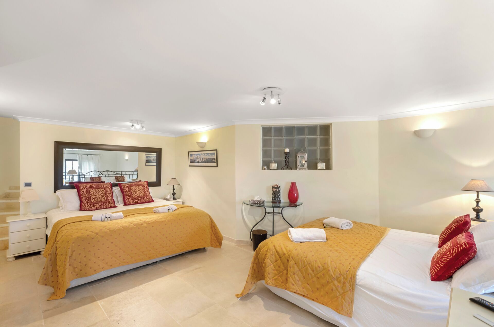 Une chambre d’hôtel avec deux lits, une petite table avec une lampe, une fenêtre agrémentée d’objets décoratifs et un miroir.