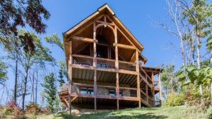 Eine mehrstöckige Holzhütte mit einem Balkon im oberen Geschoss, umgeben von Bäumen.