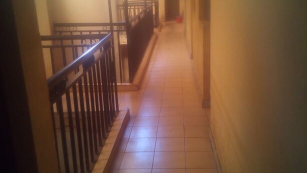 A long, narrow hallway with tiled floors and a metal railing on one side. - Desai Villa (Nairobi)
