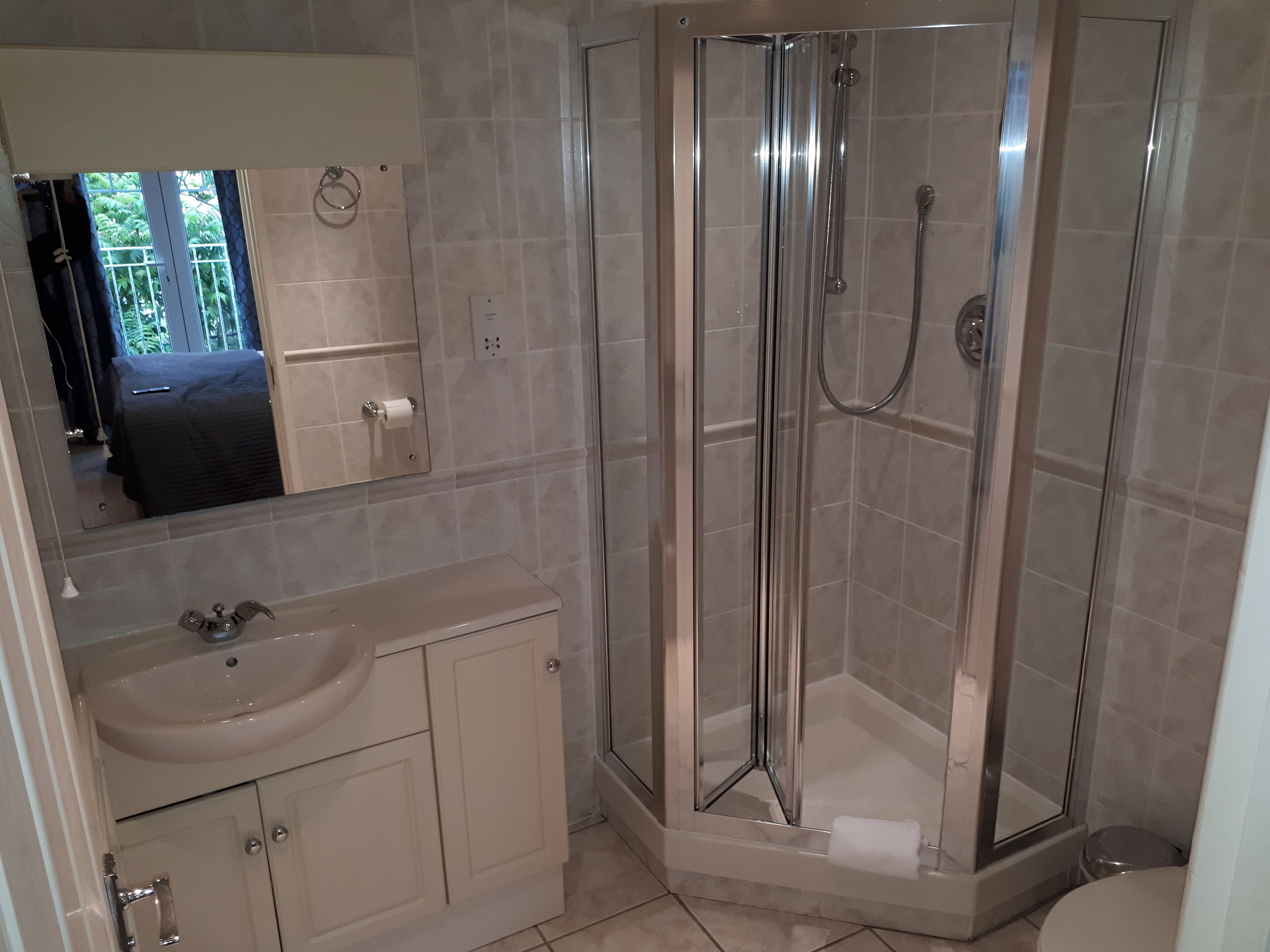 Un baño moderno con cabina de ducha de vidrio, un lavabo y un espejo.