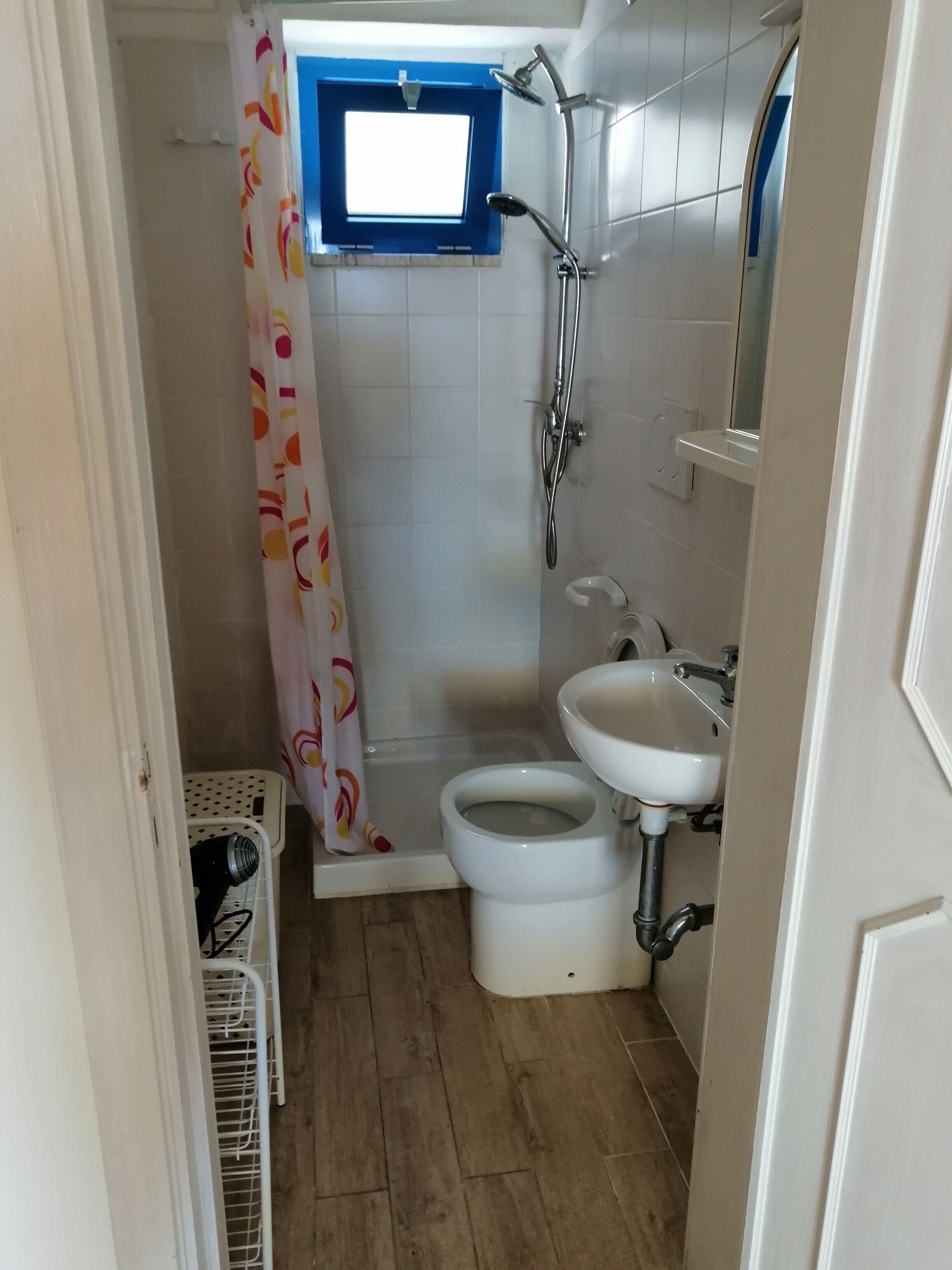 A small bathroom with a shower, toilet, and sink.