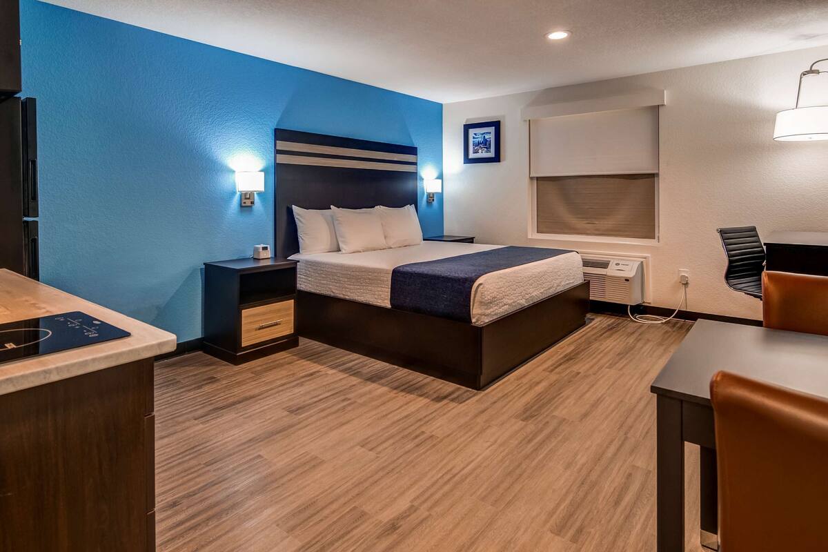A hotel room with a bed, bedside tables, a desk, and a chair.