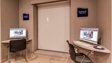 Ein Business-Center mit zwei Computern, jeweils ausgestattet mit Bildschirm, Tastatur und Stuhl.