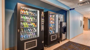 Corredor com máquinas de venda automática e um refrigerador.