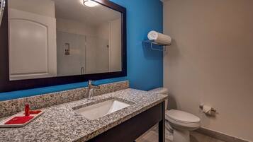 A bathroom with a granite countertop sink, a mirror, a towel rack, and a toilet.