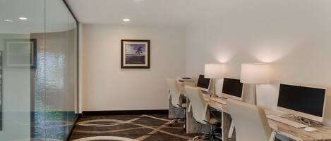 A conference room with glass walls, a patterned carpet, and a framed picture on the wall.