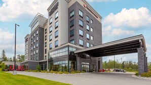 Un hotel moderno con techo plano, varios pisos y entrada cubierta.
