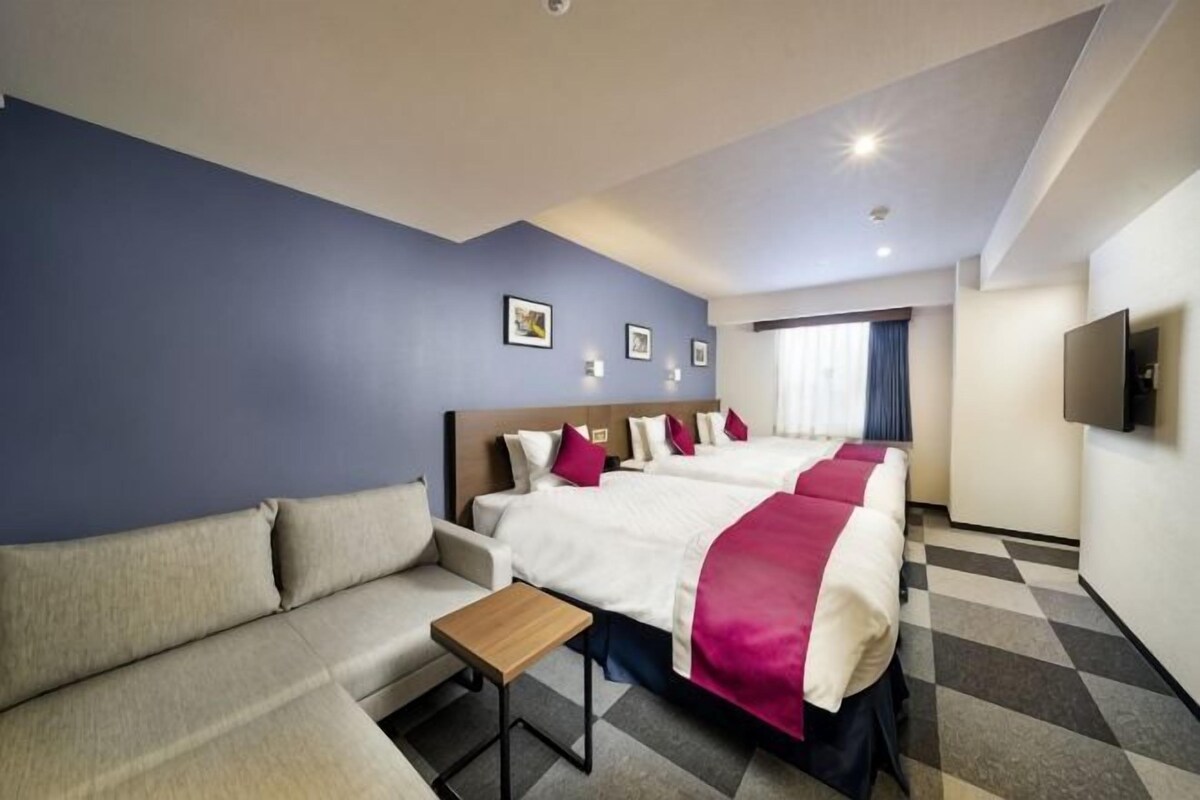 Une chambre d’hôtel avec un lit, un canapé, une petite table et un téléviseur.