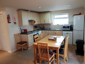A compact kitchen with a dining table, chairs, a stove, a microwave, and a refrigerator.