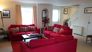 A living room with two red sofas, a coffee table, and a staircase.