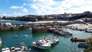 A harbor with various boats docked, a sandy beach, and buildings in the background.