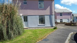 A two-story pink house with a front door, a small porch, and a visible window.
