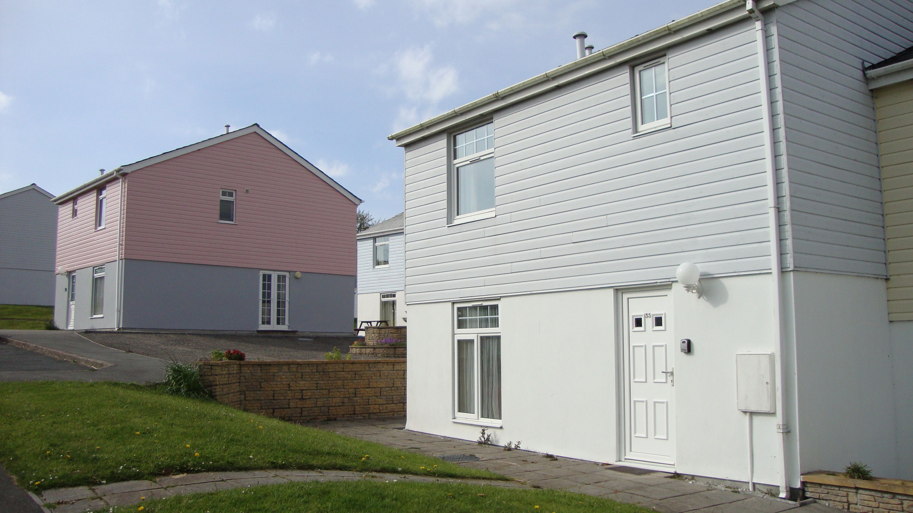 A residential area with two houses, one with pink siding and another with white siding.