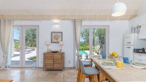 Une cuisine spacieuse dotée d’un grand îlot central, d’un coin repas et offrant une vue sur l’extérieur.