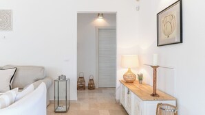 Un couloir avec un canapé, une table sur laquelle se trouve une lampe, une bougie et un tableau encadré accroché au mur.