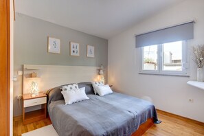 A bedroom with a bed, bedside tables, a nightstand, a window with a view, and framed botanical prints on the wall. - The sandy beach is only a few minutes' walk away (Medulin)