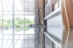 Una habitación con un amplio ventanal, un escritorio de metal y una estantería.