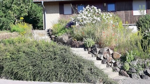 A house with a tiled roof, a brick exterior, and a garden with various plants and flowers.