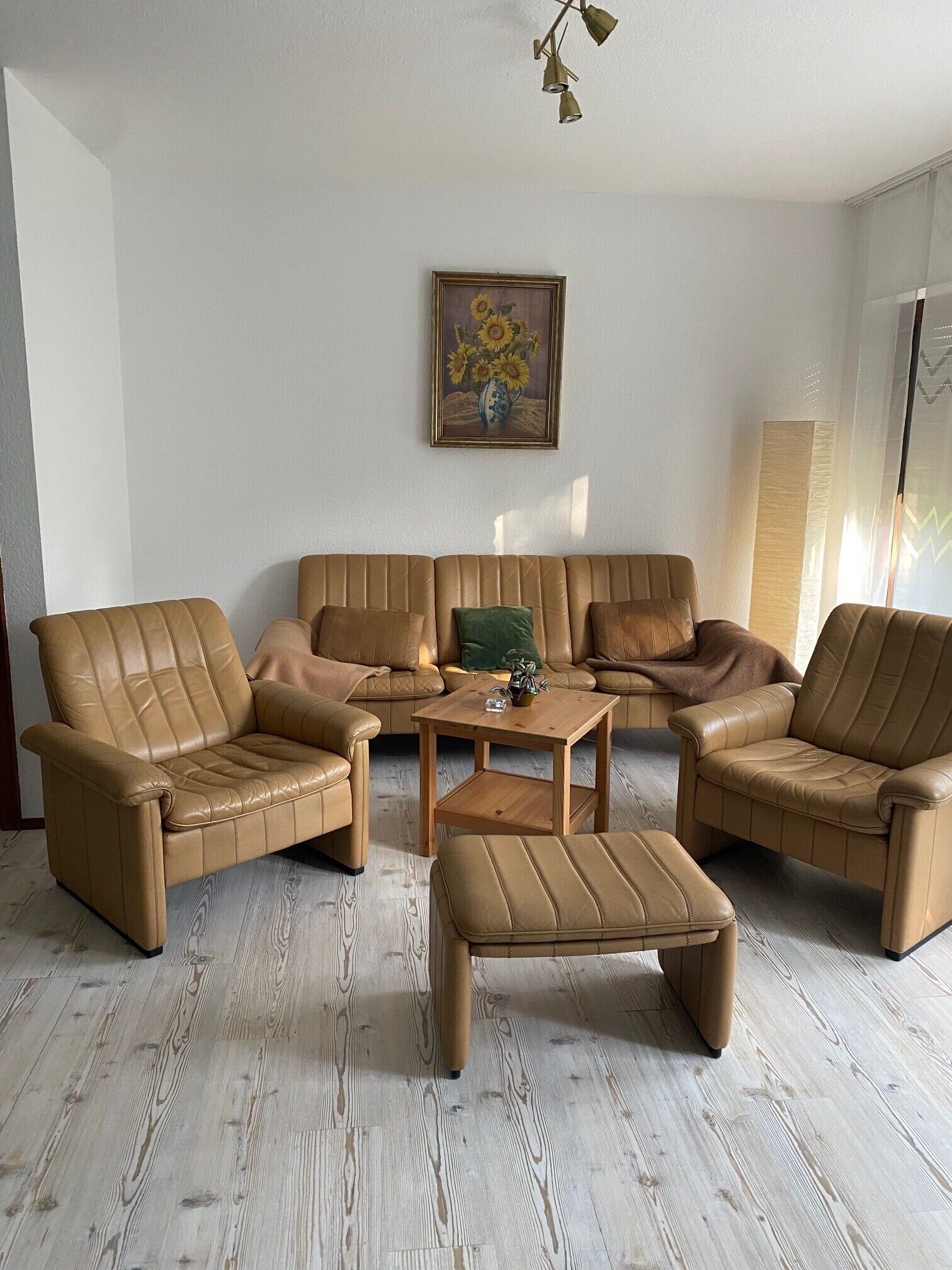 Una sala de estar con un sofá de cuero marrón, dos sillones y una mesa de centro.