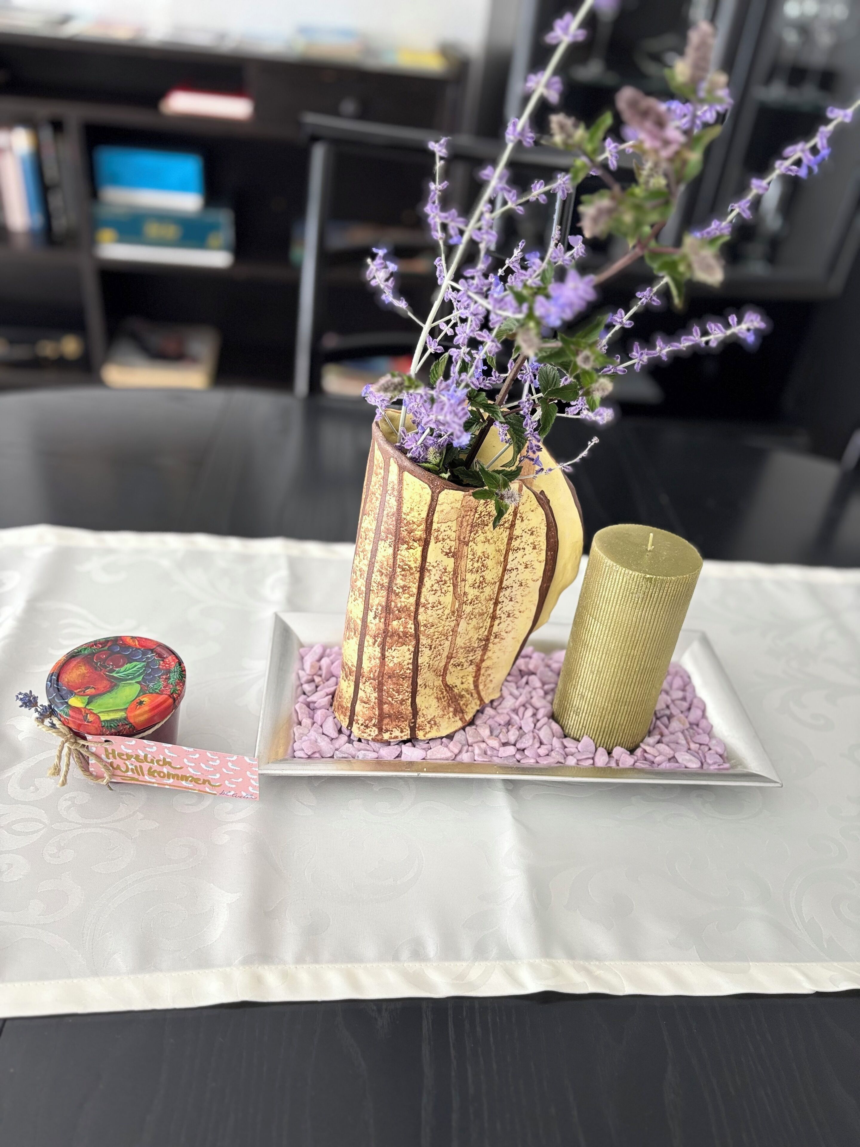 Una mesa con un jarrón decorativo, una vela y un cuenco pequeño.
