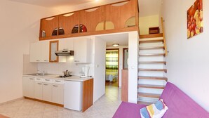 A compact apartment with a kitchenette, a purple sofa, and a staircase leading to an upper level. - Just 100 meters to beach and sea view (Medulin)