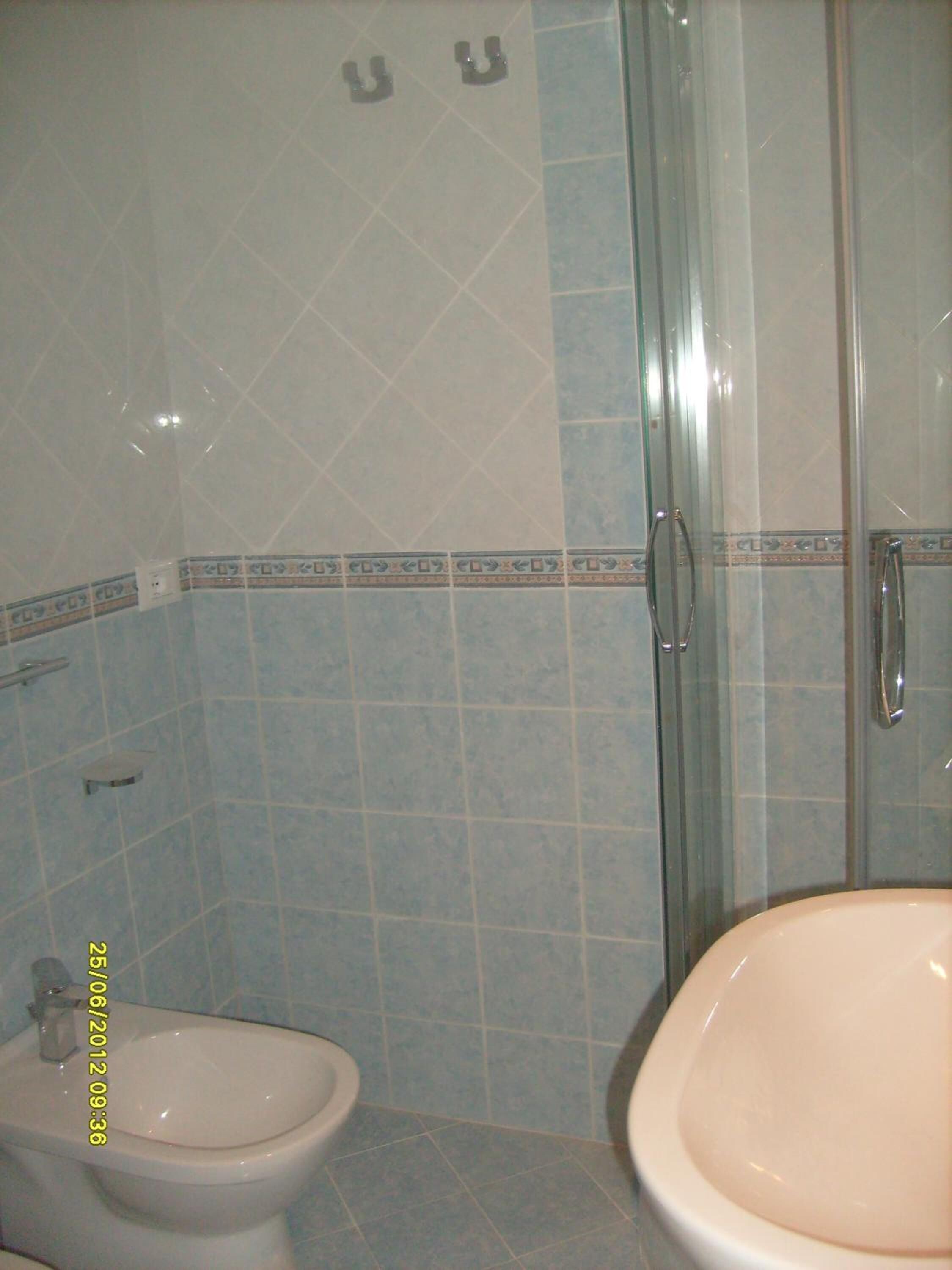 A bathroom with a toilet, a sink, and a glass shower enclosure.