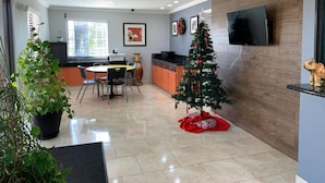 Een moderne keuken met een eethoek, een kleine kerstboom en een flatscreen televisie aan de muur.