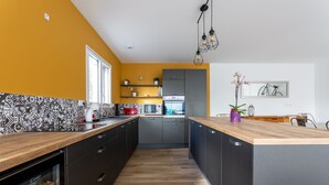 A modern kitchen with a wooden countertop, built-in appliances, and a backsplash with a geometric pattern. - VILLA SAINT ANTOINE - 9 people (Plouescat)