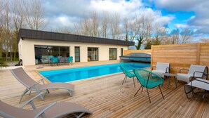 A modern outdoor pool area with lounge chairs and a wooden deck. - VILLA SAINT ANTOINE - 9 people (Plouescat)