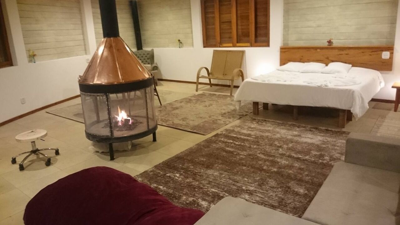 Une pièce chaleureuse avec un poêle à bois, un lit, une chaise et une petite table.