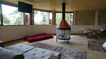 A spacious living area with a large window, a fireplace, a sofa, and a dining table.