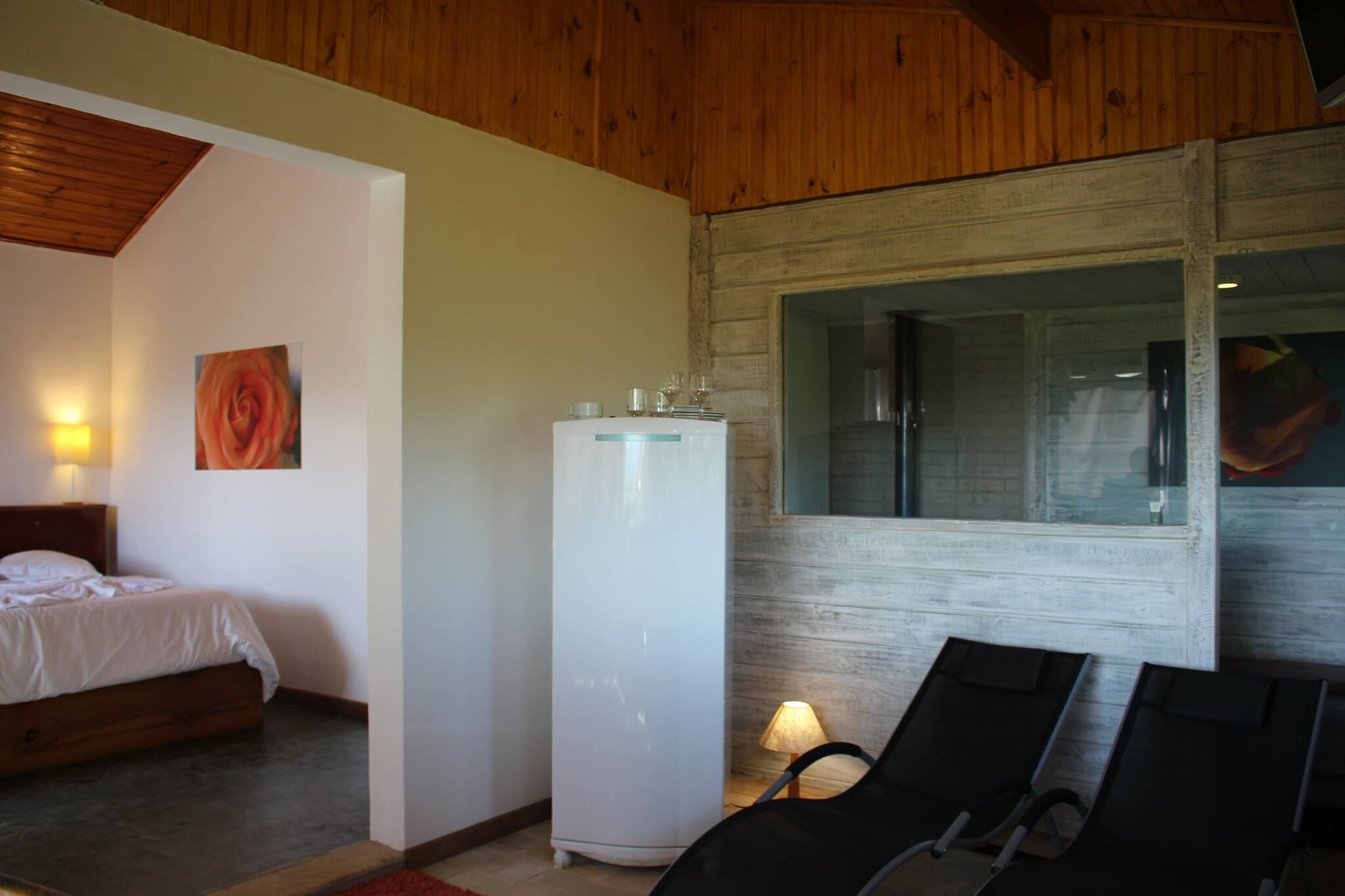 Een slaapkamer met een bed, een witte koelkast, een raam en een stoel.
