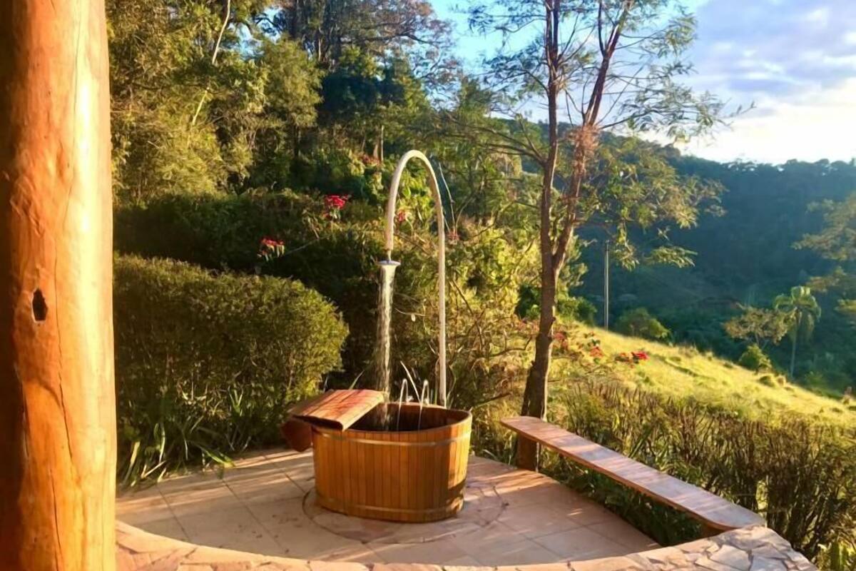 Une terrasse en pierre avec un bain à remous en bois et un banc en bois.