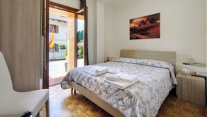 A bedroom with a bed, a chair, a painting on the wall, and a view through an open door. - Hotel da Marco (Vigo di Cadore)
