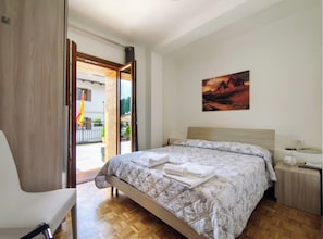 A bedroom with a bed, a chair, a painting on the wall, and a view through an open door. - Hotel da Marco (Vigo di Cadore)