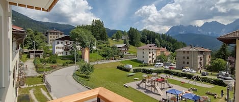 A residential area with multiple buildings, a playground, and a clear view of mountains in the background.
