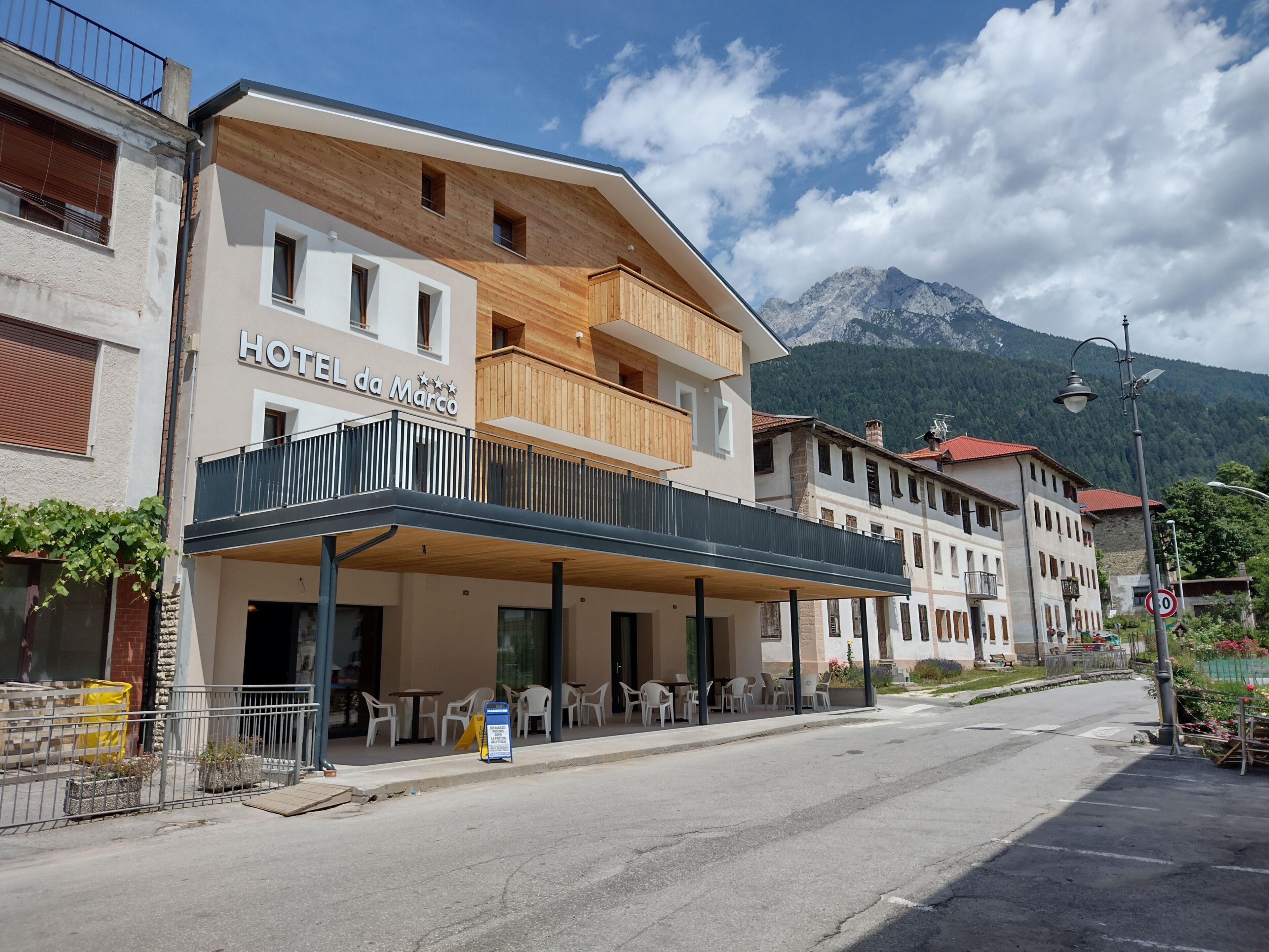 A hotel with a wooden facade, outdoor seating area, and a mountain backdrop.