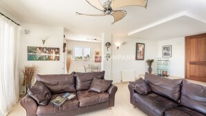 A spacious living room with two brown leather sofas, a ceiling fan, and a dining area in the background. - Wonderful villa with country views, private pool, sleeps 6, AC (Binixica)