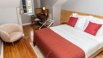 Une chambre avec un plancher en bois, un lit avec une literie blanche et rouge, un bureau avec une chaise et une lampe.