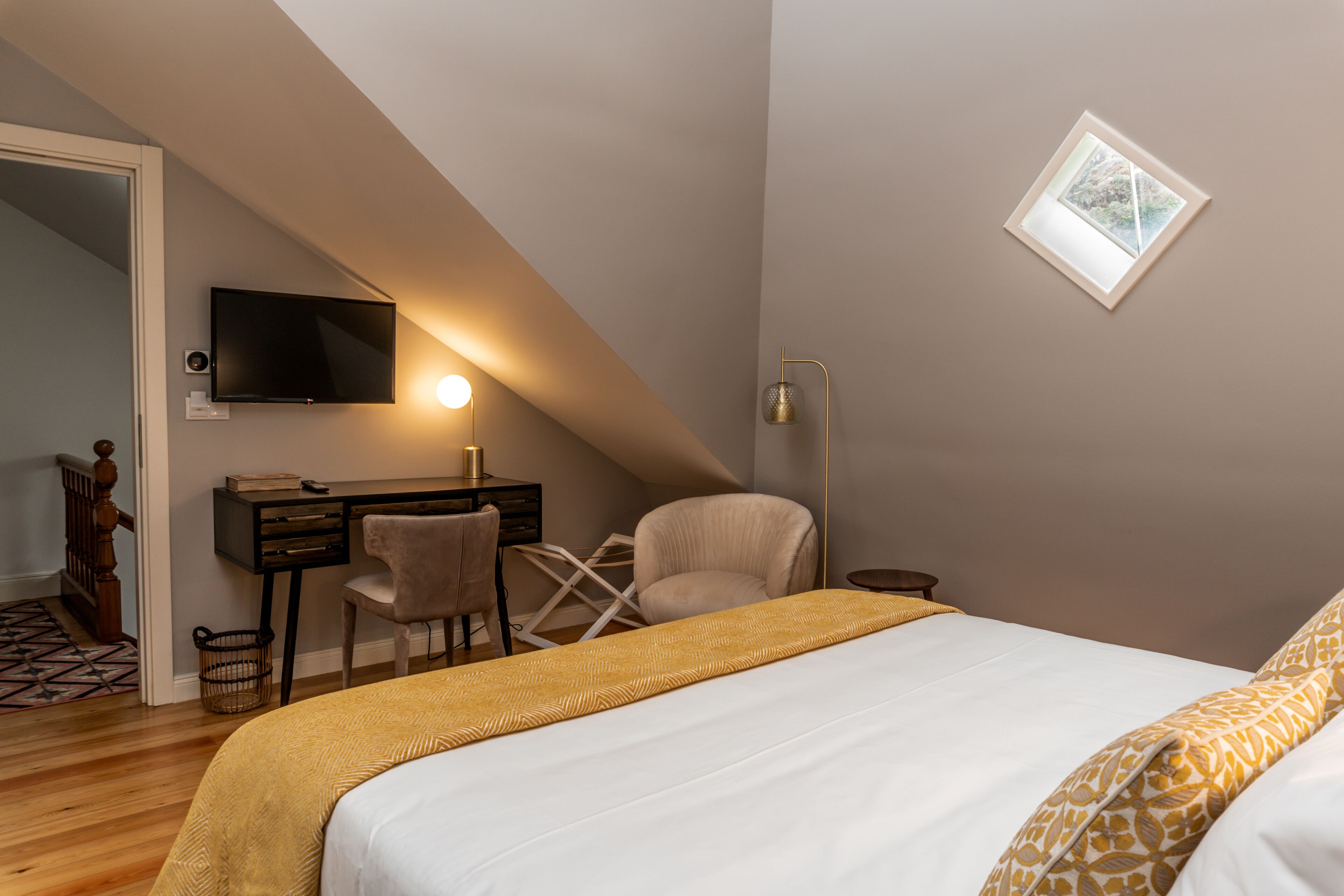 Una camera da letto con un letto, una scrivania, una sedia e un televisore montato a parete.