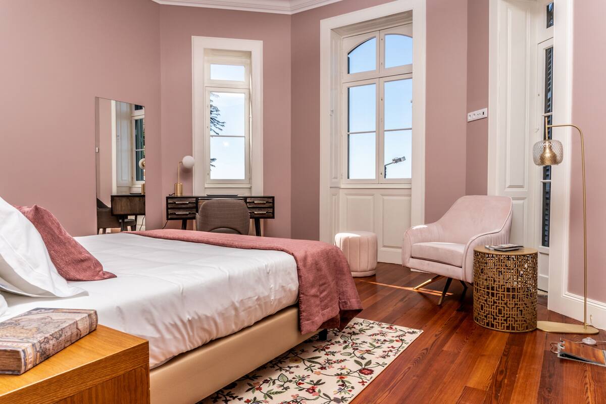 A bedroom with a bed, a desk, a chair, and a small round table.
