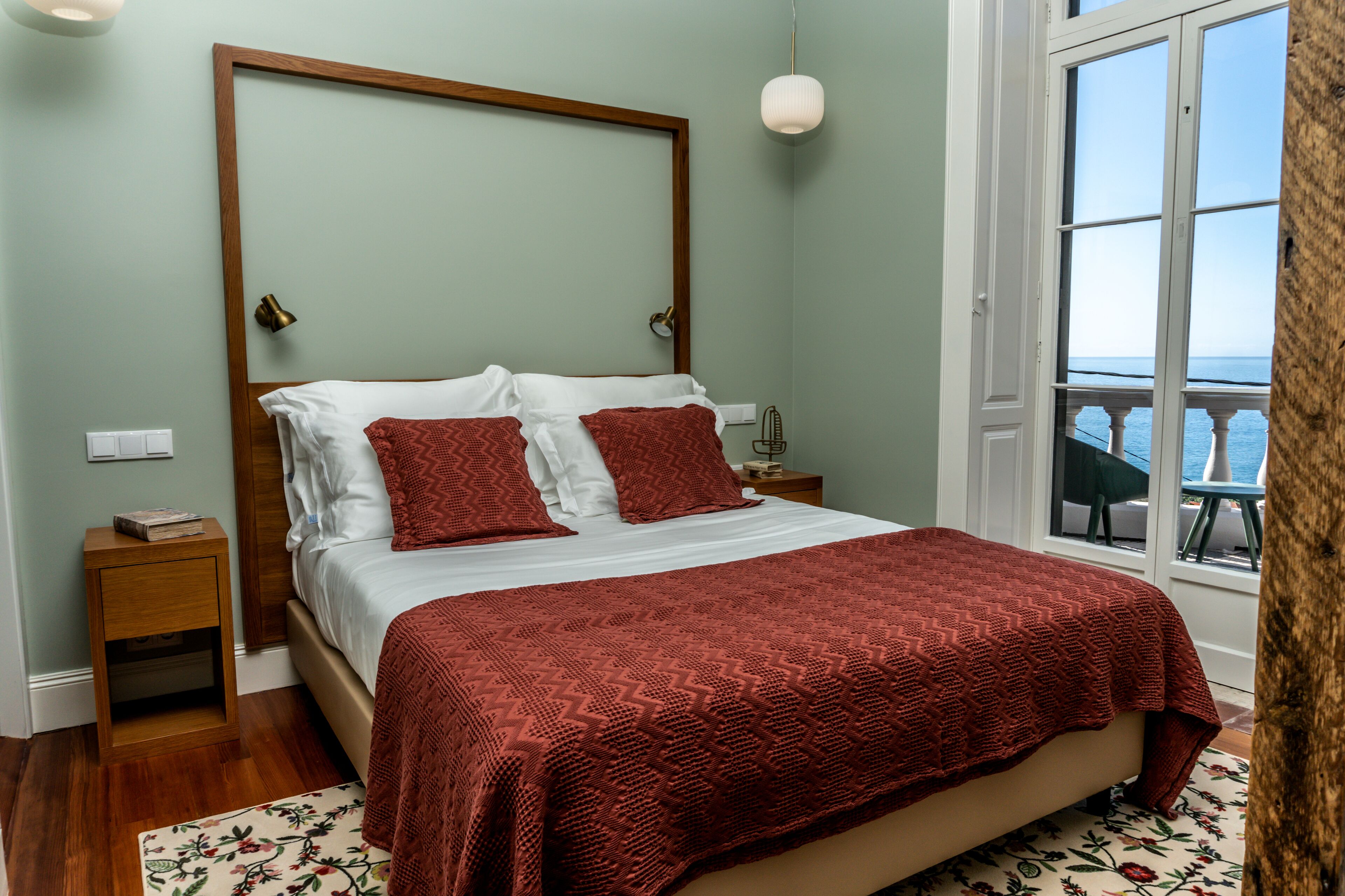 Un dormitorio con una cama grande, cabecera de madera, mesita de noche y ventana con vistas.