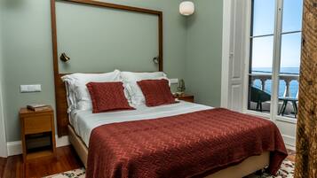 Un dormitorio con una cama grande, cabecera de madera, mesita de noche y ventana con vistas.