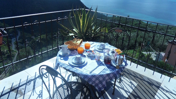A table set with breakfast items on a balcony overlooking a coastal landscape. - B&B Il Vigneto in the heart of the Cinque Terre (Volastra)