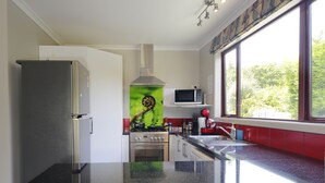 Een keuken met een roestvrijstalen koelkast, een magnetron, een fornuis en een spoelbak.