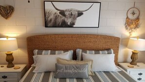 Une chambre à coucher avec une couvre-lit à rayures, une tête de lit à motifs tissés et deux tables de chevet avec des lampes.