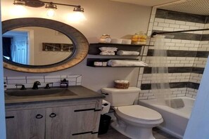 Een bad/douchecombinatie, een haardroger, handdoeken, zeep