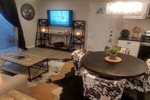 A cozy living room with a TV, a round table with chairs, a coffee table, and a cowhide rug. - Patio Paradise, 1.6 miles to FSU Stadium! (Tallahassee)