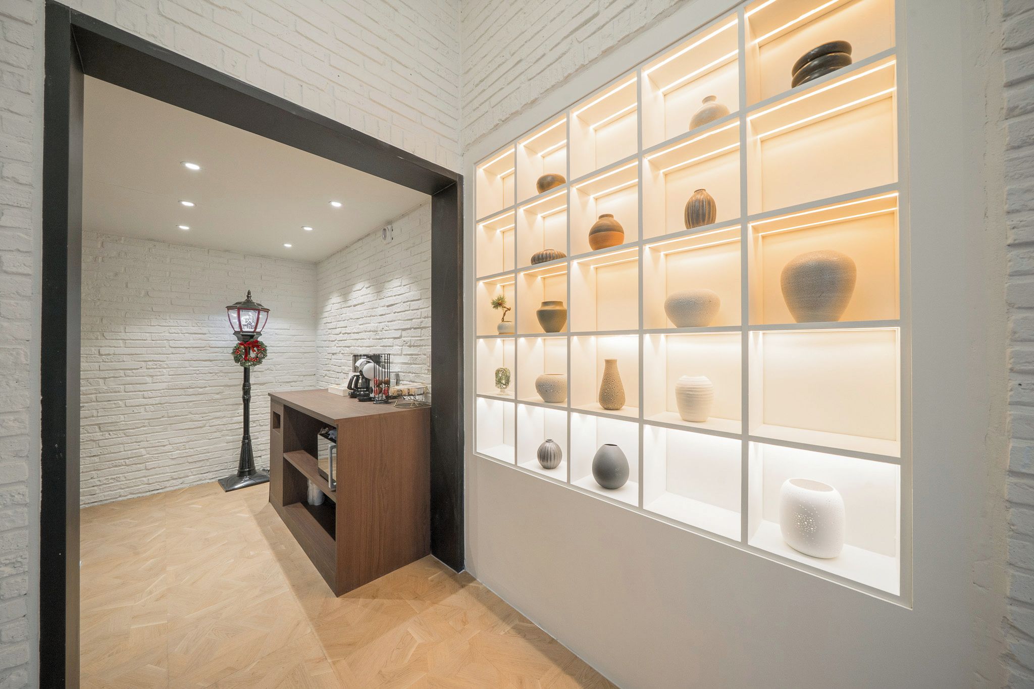 A reception area with a wooden desk, a wall-mounted display of vases, and a brick wall.
